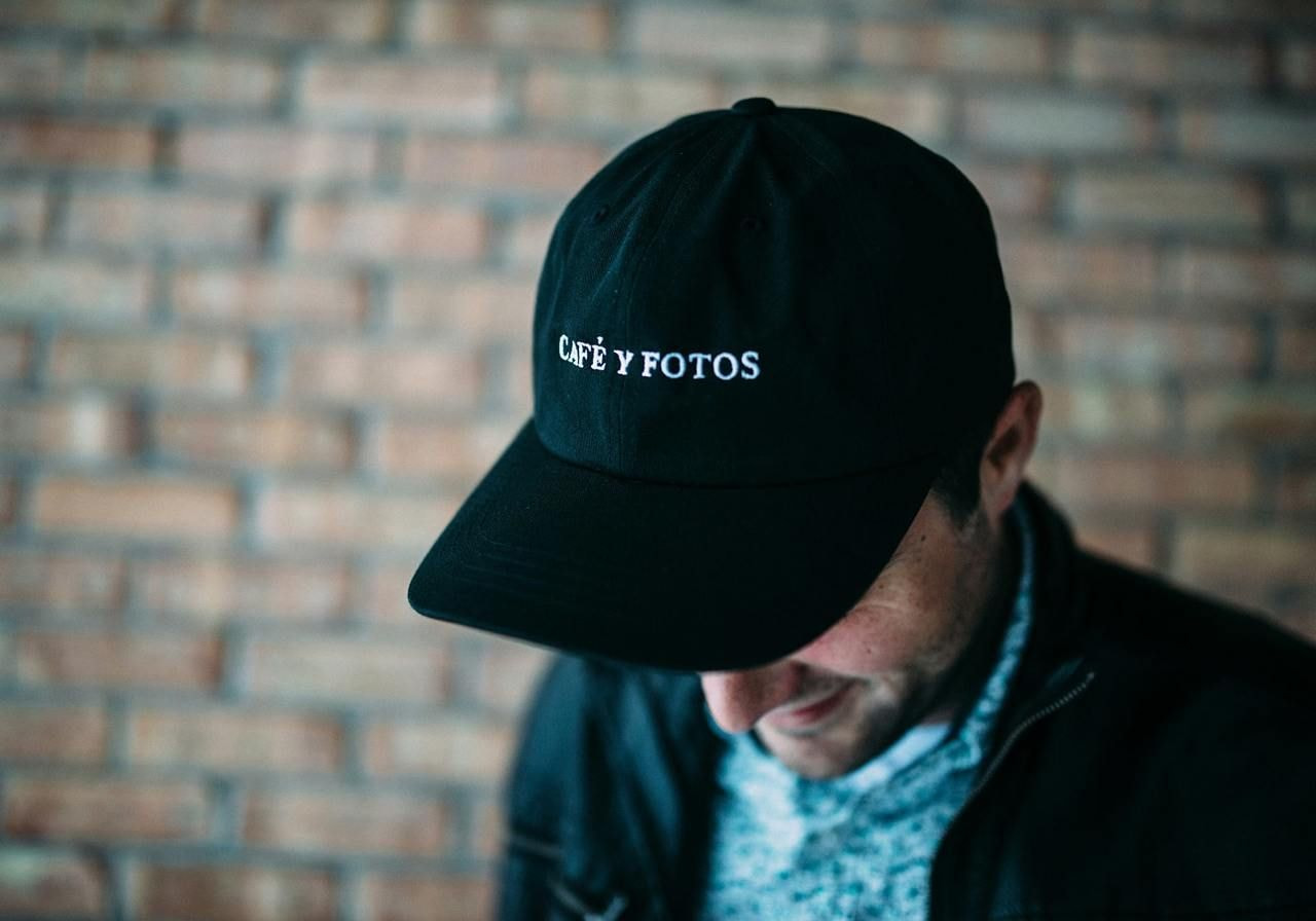 A man wearing a custom black cap with embroidered text.