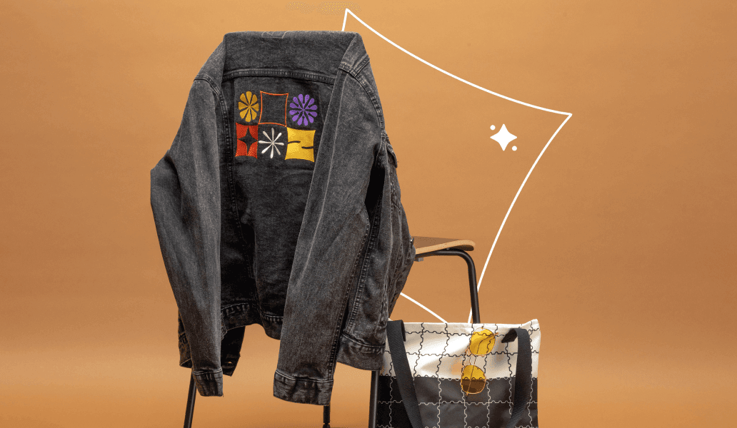 photo of an embroidered jacket hanging on a chair and a custom tote bag